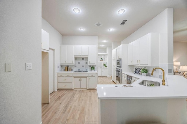 kitchen featuring sink, stainless steel appliances, white cabinets, and kitchen peninsula