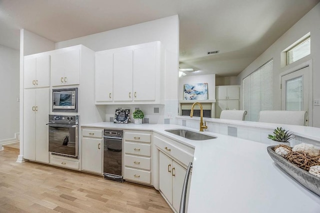 kitchen featuring sink, stainless steel microwave, white cabinetry, and oven