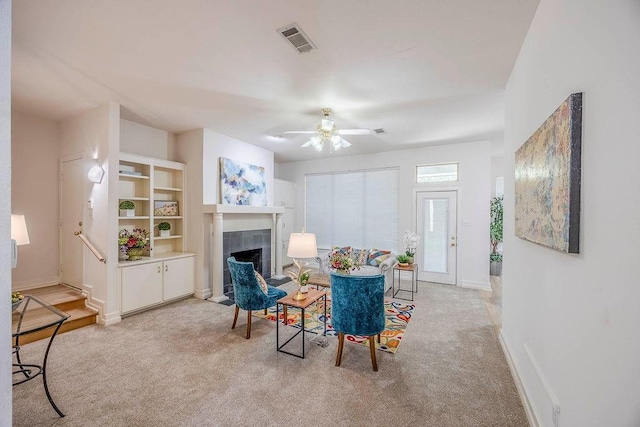 sitting room with a tile fireplace, ceiling fan, and light colored carpet