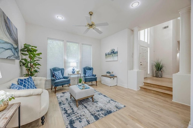 living room with decorative columns, ceiling fan, light hardwood / wood-style floors, and plenty of natural light