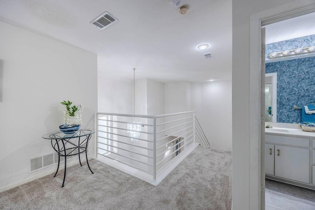 corridor with sink and light colored carpet