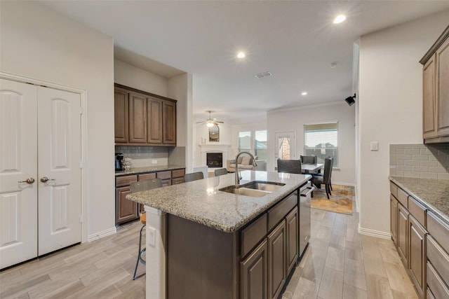 kitchen featuring sink, stainless steel dishwasher, a kitchen island with sink, and tasteful backsplash