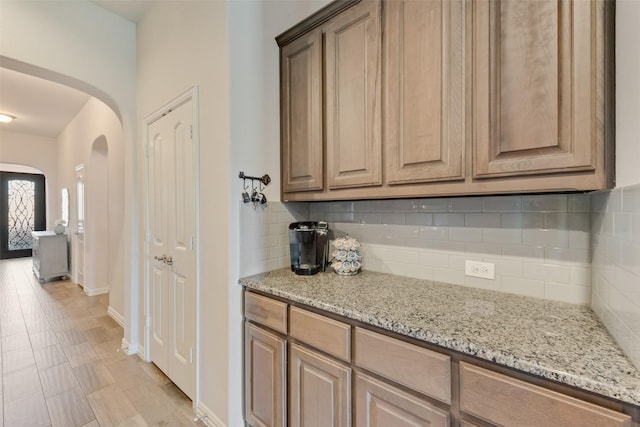 kitchen featuring decorative backsplash and light stone counters