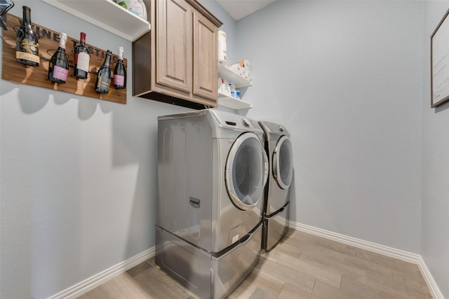 clothes washing area with light hardwood / wood-style flooring, cabinets, and independent washer and dryer