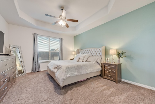 carpeted bedroom featuring a raised ceiling and ceiling fan