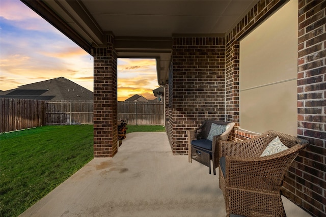 patio terrace at dusk featuring a lawn