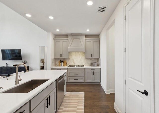 kitchen featuring appliances with stainless steel finishes, gray cabinetry, custom range hood, dark hardwood / wood-style flooring, and sink