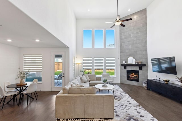 living room featuring ceiling fan, a tile fireplace, and dark hardwood / wood-style floors