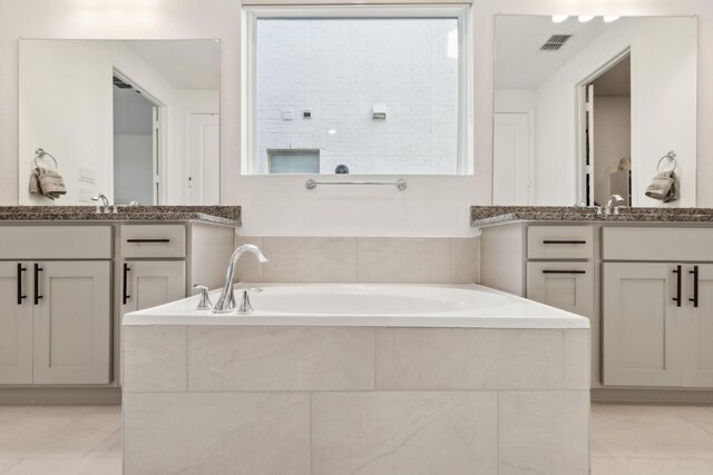 bathroom featuring vanity, tile patterned flooring, and tiled bath