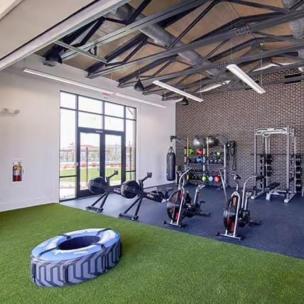 workout area with golf simulator, high vaulted ceiling, and brick wall