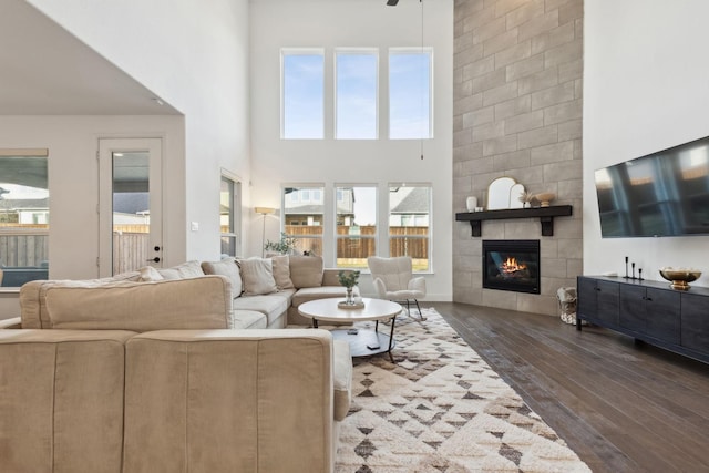 living room with a towering ceiling, a tile fireplace, and dark hardwood / wood-style floors