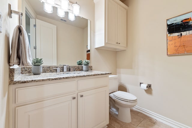 bathroom with toilet, vanity, and tile patterned floors