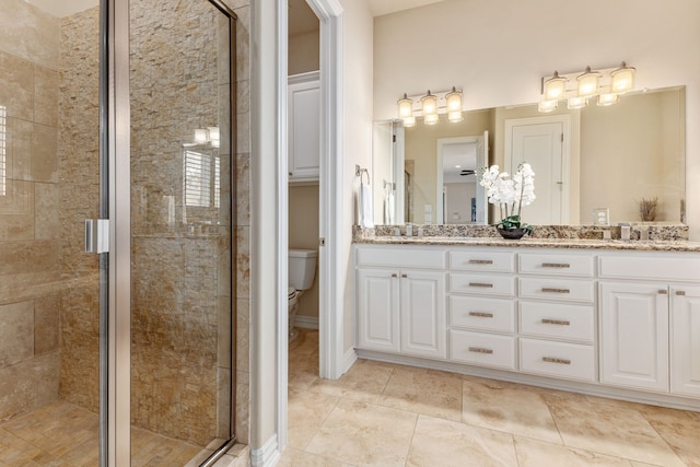 bathroom featuring a shower with door, vanity, and toilet