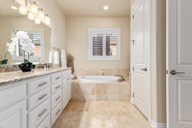 bathroom with tiled bath and vanity