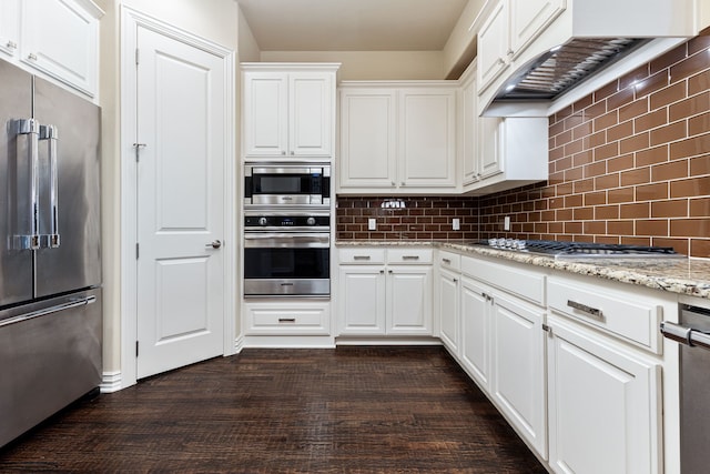 kitchen featuring custom exhaust hood, appliances with stainless steel finishes, light stone counters, white cabinetry, and tasteful backsplash