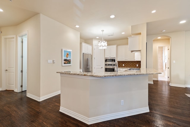 kitchen featuring built in appliances, decorative light fixtures, white cabinets, light stone counters, and dark hardwood / wood-style flooring