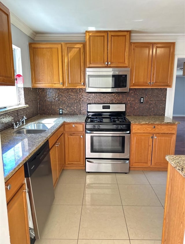 kitchen featuring appliances with stainless steel finishes, crown molding, light stone countertops, light tile patterned floors, and sink