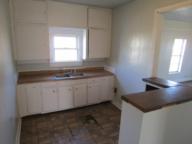 kitchen featuring sink, white cabinets, wood walls, and kitchen peninsula