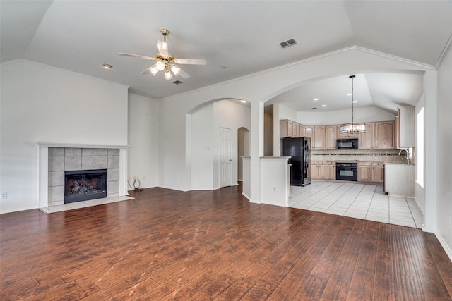 unfurnished living room featuring lofted ceiling, a tile fireplace, ceiling fan, and light hardwood / wood-style floors