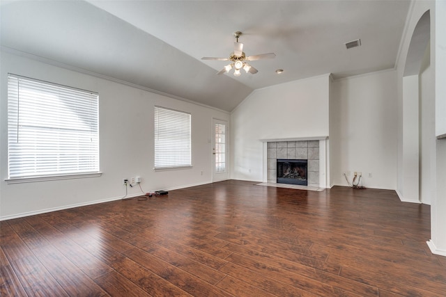 unfurnished living room with a tiled fireplace, ceiling fan, vaulted ceiling, and dark wood-type flooring