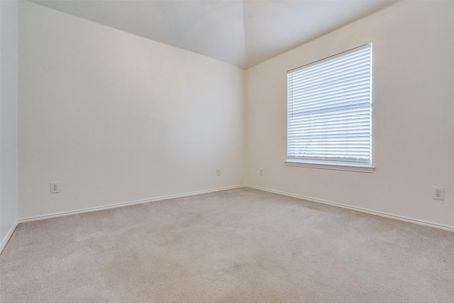 spare room with light carpet and lofted ceiling