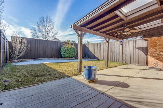 wooden terrace featuring ceiling fan and a lawn