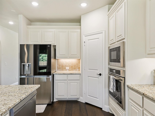 kitchen with appliances with stainless steel finishes, dark wood-type flooring, white cabinets, and light stone countertops