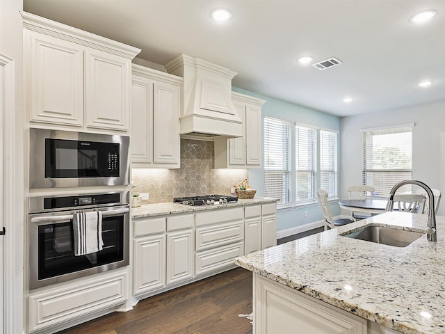 kitchen featuring stainless steel appliances, sink, custom exhaust hood, backsplash, and dark hardwood / wood-style floors