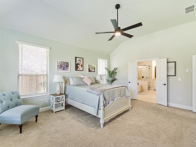 carpeted bedroom featuring vaulted ceiling, ensuite bath, ceiling fan, and multiple windows