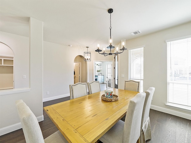 dining space with dark wood-type flooring and a chandelier