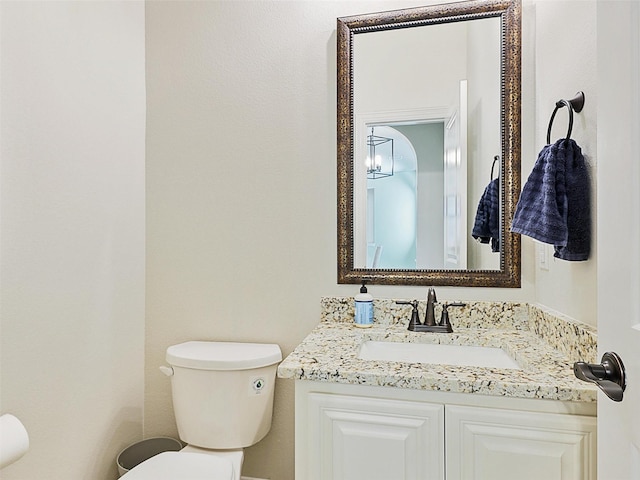 bathroom featuring toilet, vanity, and a chandelier