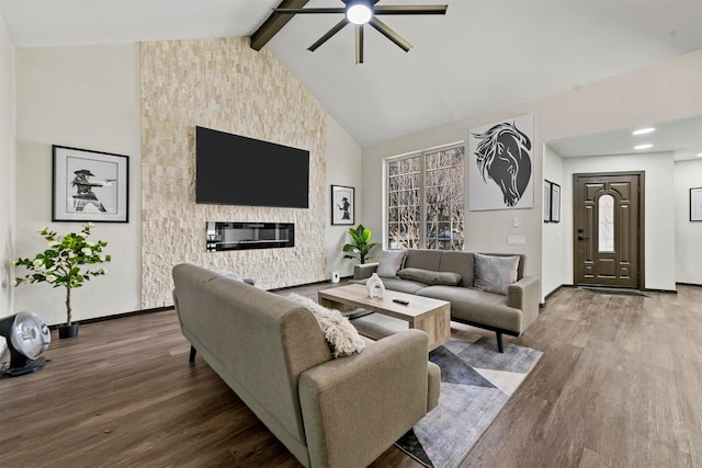 living room featuring beamed ceiling, high vaulted ceiling, ceiling fan, wood-type flooring, and a stone fireplace