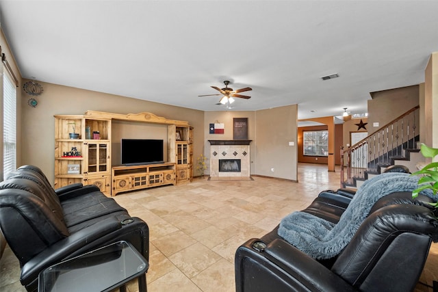 living room with a tiled fireplace and ceiling fan