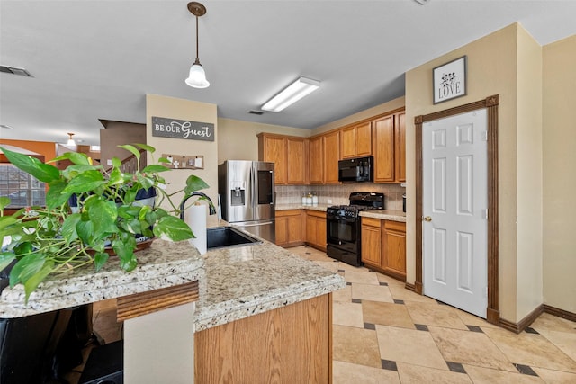 kitchen with a sink, brown cabinets, black appliances, tasteful backsplash, and pendant lighting