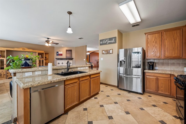 kitchen with appliances with stainless steel finishes, decorative light fixtures, tasteful backsplash, sink, and a kitchen island with sink