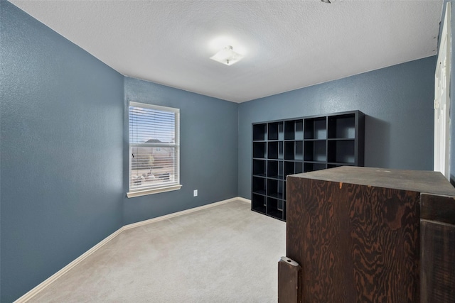 carpeted home office featuring a textured wall, a textured ceiling, and baseboards