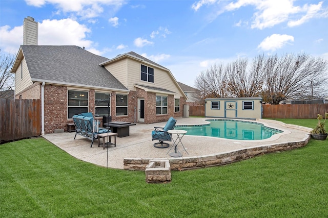 rear view of house with a fenced backyard, a fire pit, brick siding, an outdoor structure, and a patio area