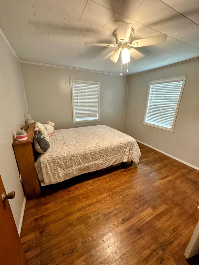 bedroom featuring ceiling fan, ornamental molding, and dark hardwood / wood-style floors