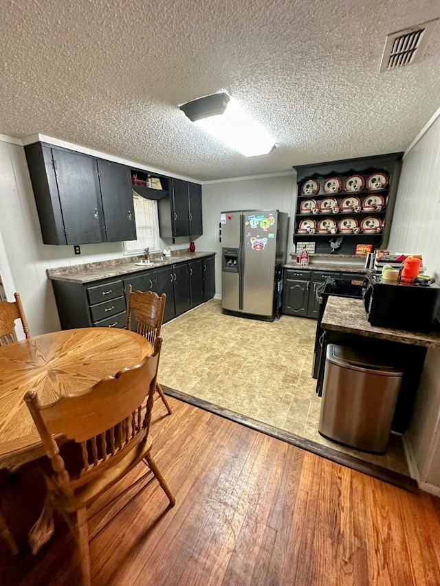 kitchen with a textured ceiling, stainless steel fridge with ice dispenser, light hardwood / wood-style flooring, and sink