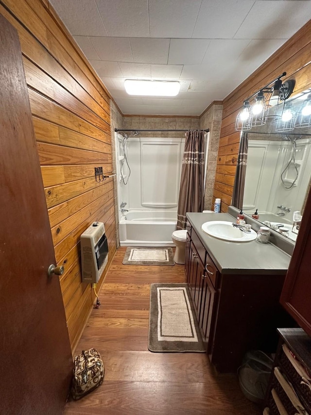 full bathroom with wooden walls, shower / tub combo, toilet, heating unit, and vanity