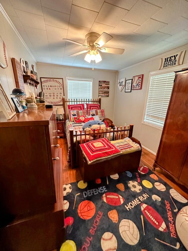 bedroom with ceiling fan, dark wood-type flooring, and crown molding