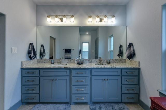 full bath featuring double vanity, baseboards, and a sink