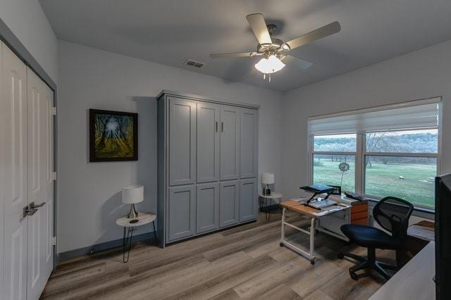 office with light wood-style floors, ceiling fan, visible vents, and baseboards