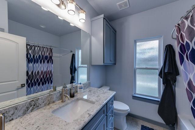 bathroom featuring curtained shower, toilet, visible vents, vanity, and baseboards