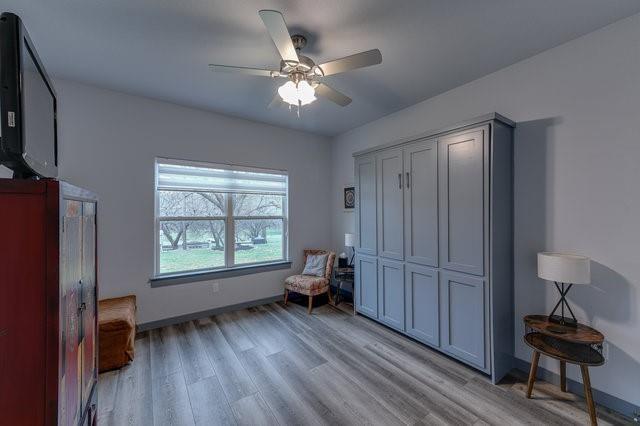 interior space with ceiling fan, light wood finished floors, and baseboards