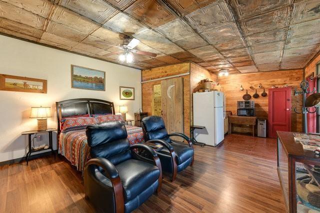 bedroom with dark wood-type flooring, freestanding refrigerator, and an ornate ceiling