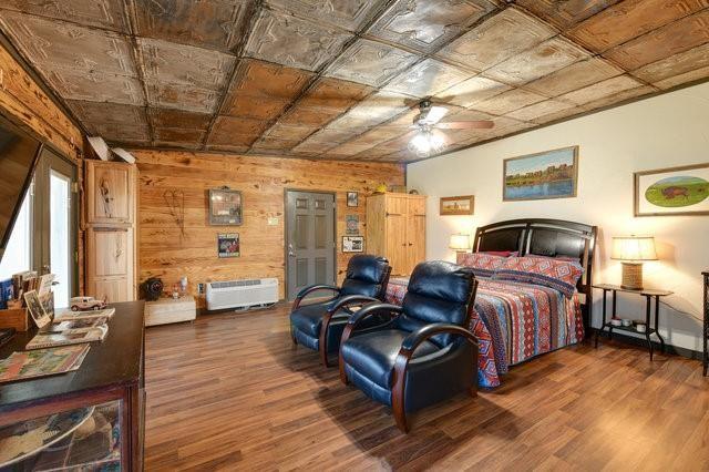 bedroom featuring an ornate ceiling, wood walls, and wood finished floors