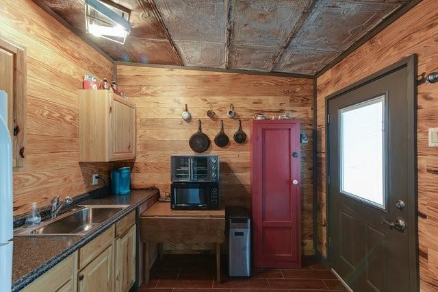 kitchen featuring dark countertops, black microwave, a sink, and wooden walls