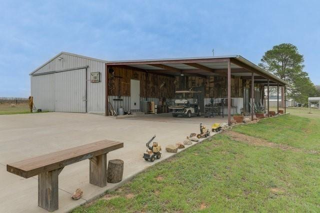 exterior space with an outbuilding, a pole building, a lawn, and a detached garage