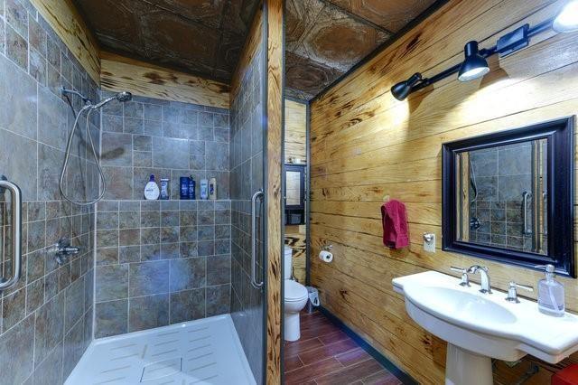 bathroom with toilet, a shower stall, wood tiled floor, and a sink